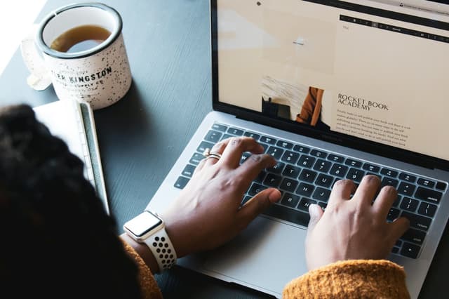 Professional typing on a laptop at a desk with a cup of tea